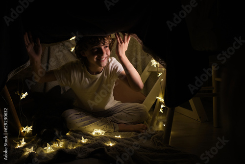 Fotografija Happy boy sitting in blanket fort