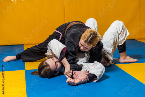 Young girls practice Brazilian jiu jitsu in the gym