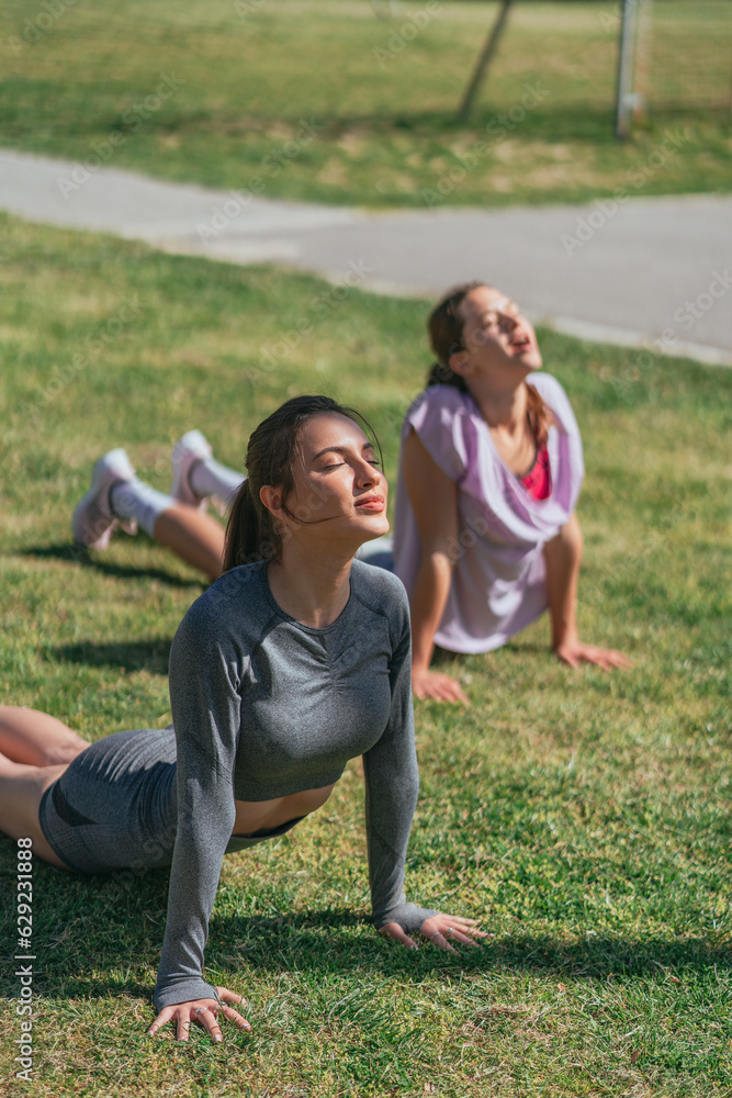 Two girls stretching their spines. Training outdoors Two girls stretching their spines. Training outdoors