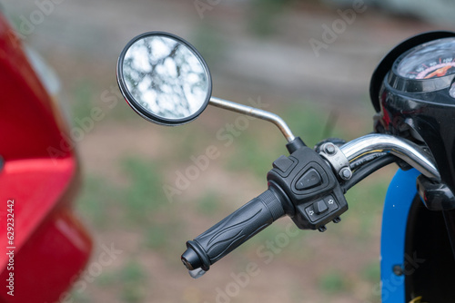 Close-up at handle part of the traiditonal engine motorcycle or motorbike, there are has braking system, lighting signal, horn and side mirror. Transportation equipment object photo.