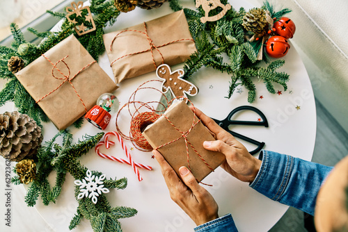 Photography Faceless person putting present wrapped in paper on Christmas table