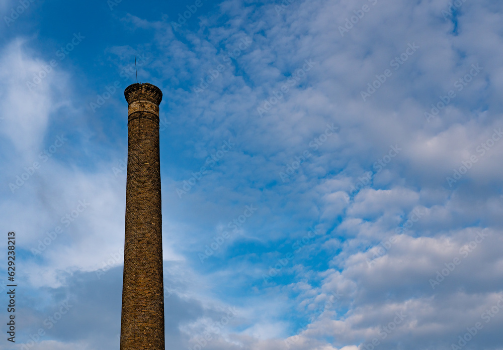 The tip of an old brick chimney on blue sky at the evening.