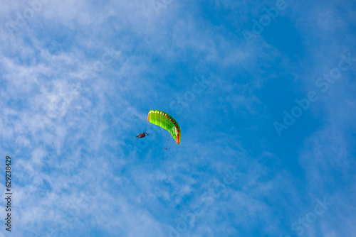 parachute in the sky. A tandem of two parachutists flies on a parachute in the blue sky