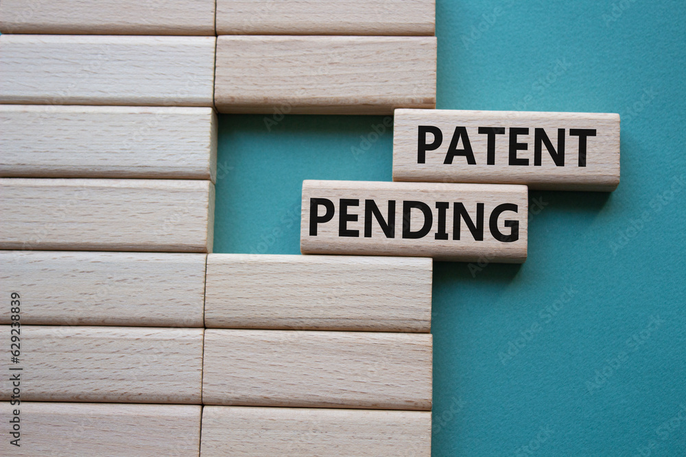 Patent Pending symbol. Concept word Patent Pending on wooden blocks. Beautiful grey green background. Business and Patent Pending concept. Copy space Patent Pending symbol. Concept word Patent Pending on wooden blocks. Beautiful grey green background. Business and Patent Pending concept. Copy space