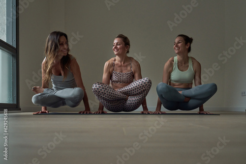 Women doing yoga arm balance exercise with crossed legs photo