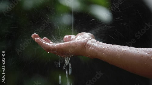 Person holding his hand under the heavy rain on the blurred background