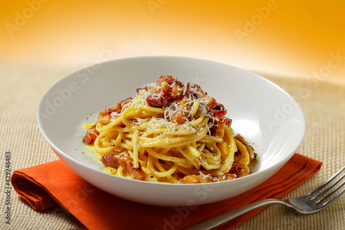 Bowl on napkin with spaghetti carbonara with grated cheese