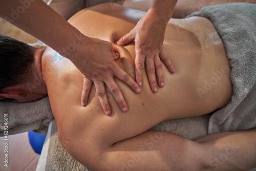 Anonymous masseuse treating client in spa salon