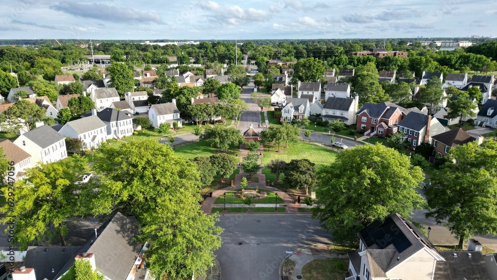 Aerial view of a residential neighborhood surrounded by lush greenery on a sunny day