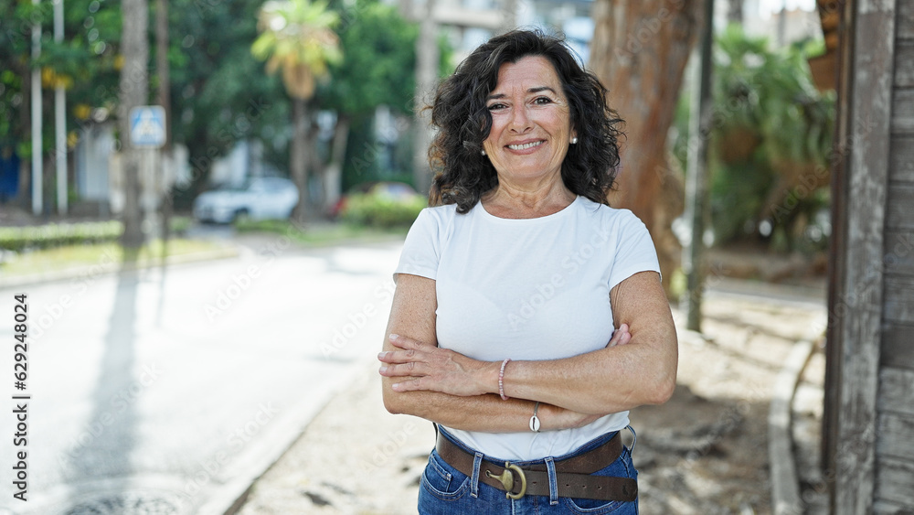 Fototapeta premium Middle age hispanic woman smiling confident standing with arms crossed gesture at park