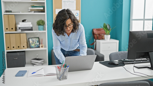 Middle age hispanic woman business worker using laptop at the office