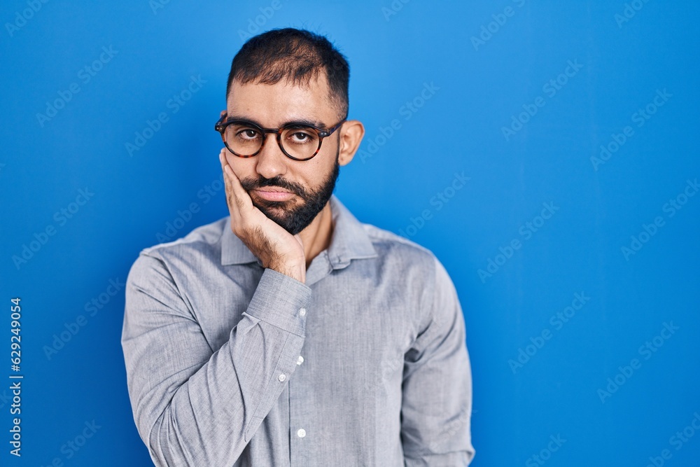 Middle east man with beard standing over blue background thinking looking tired and bored with depression problems with crossed arms. Middle east man with beard standing over blue background thinking looking tired and bored with depression problems with crossed arms.