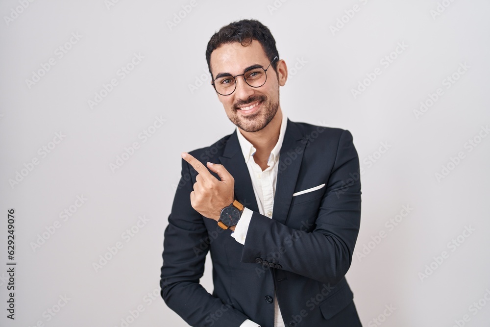 Handsome business hispanic man standing over white background cheerful with a smile on face pointing with hand and finger up to the side with happy and natural expression Handsome business hispanic man standing over white background cheerful with a smile on face pointing with hand and finger up to the side with happy and natural expression