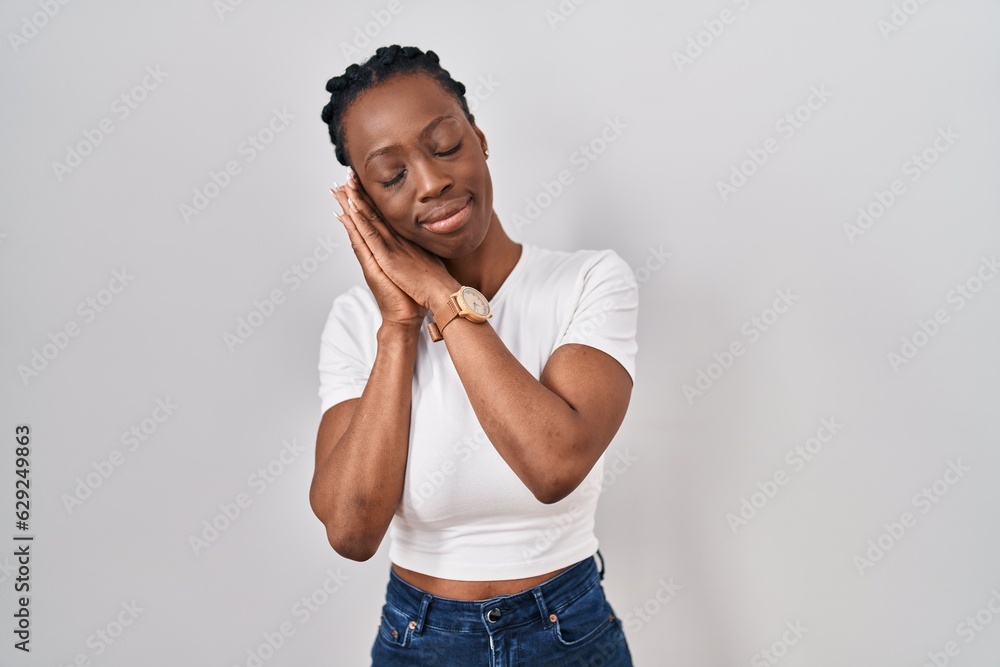 Beautiful black woman standing over isolated background sleeping tired dreaming and posing with hands together while smiling with closed eyes. Beautiful black woman standing over isolated background sleeping tired dreaming and posing with hands together while smiling with closed eyes.