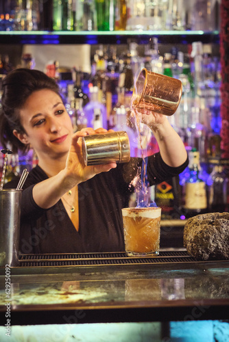 Smiling female bartender mixing burning cocktail at counter