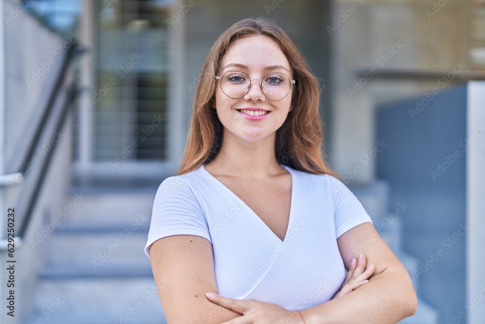 Young blonde woman standing with arms crossed gesture at street Young blonde woman standing with arms crossed gesture at street