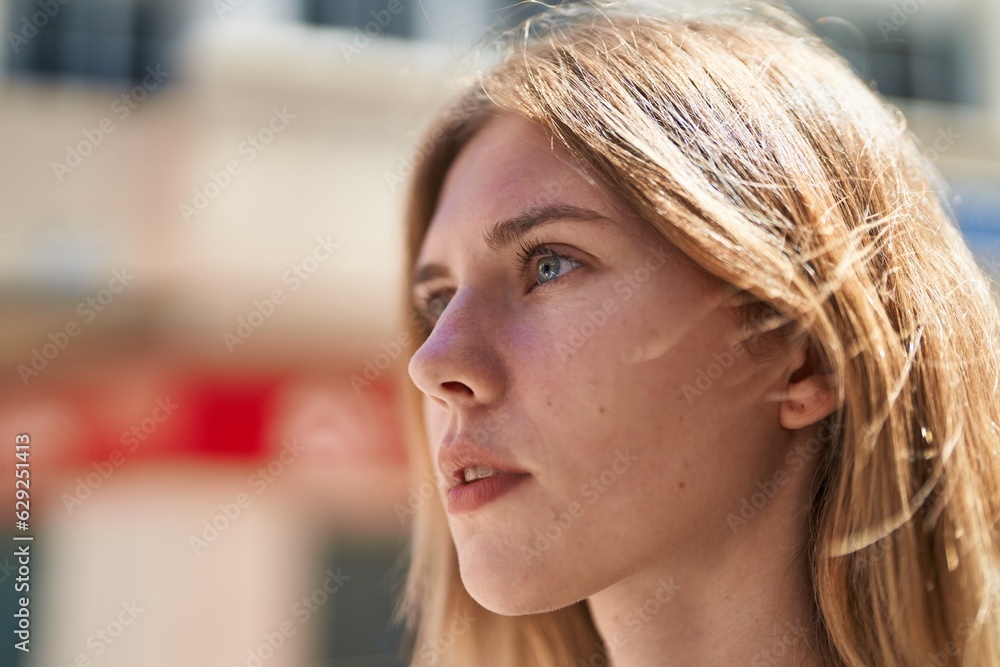 Young blonde woman looking to the side with serious expression at street Young blonde woman looking to the side with serious expression at street