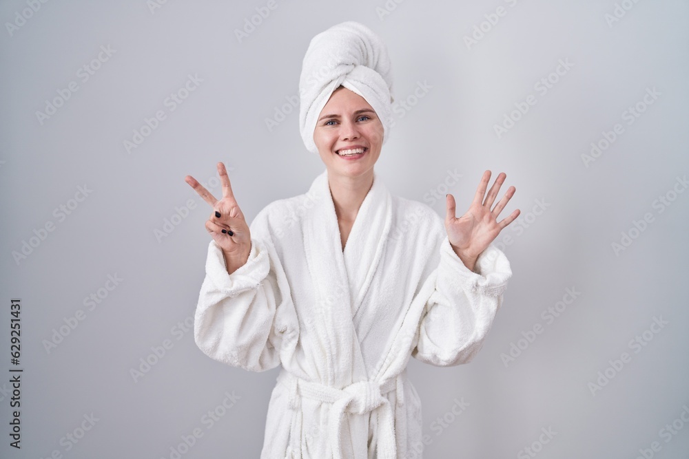 Blonde caucasian woman wearing bathrobe showing and pointing up with fingers number seven while smiling confident and happy. Blonde caucasian woman wearing bathrobe showing and pointing up with fingers number seven while smiling confident and happy.