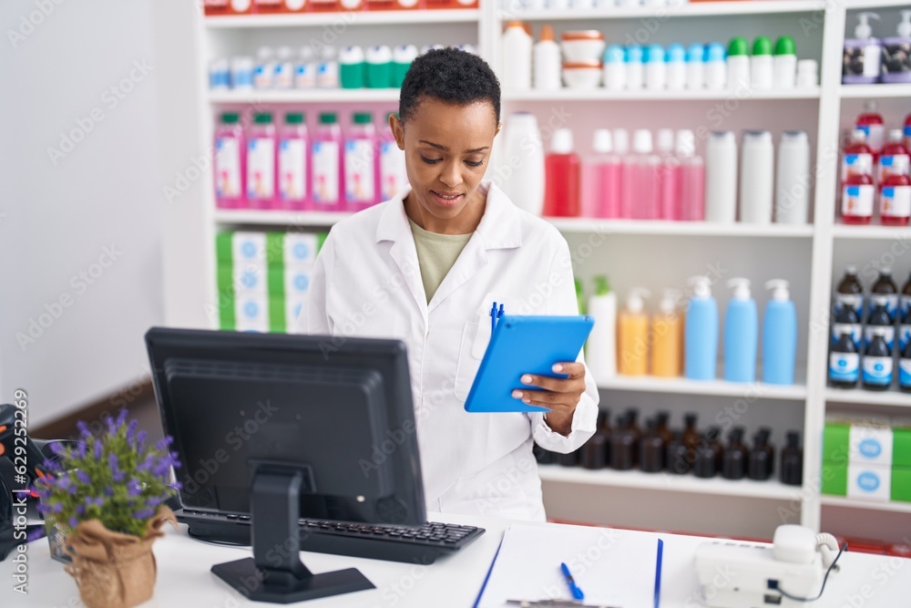 African american woman pharmacist using computer and touchpad at pharmacy