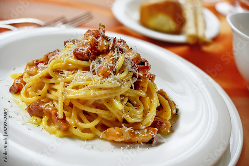 Plate with spaghetti carbonara on a laid table