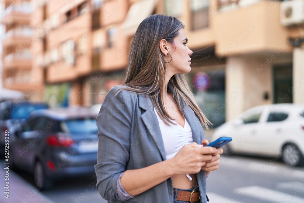 Fototapeta premium Young woman using smartphone at street