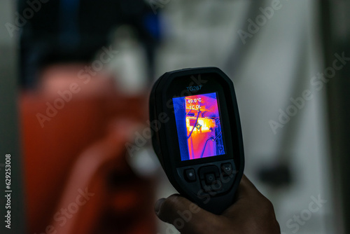 Professional Electrician use thermal infrared camera or thermometer scanning electrical system for preventive maintenance,Industrial thermography,Thermal image of power electric. photo
