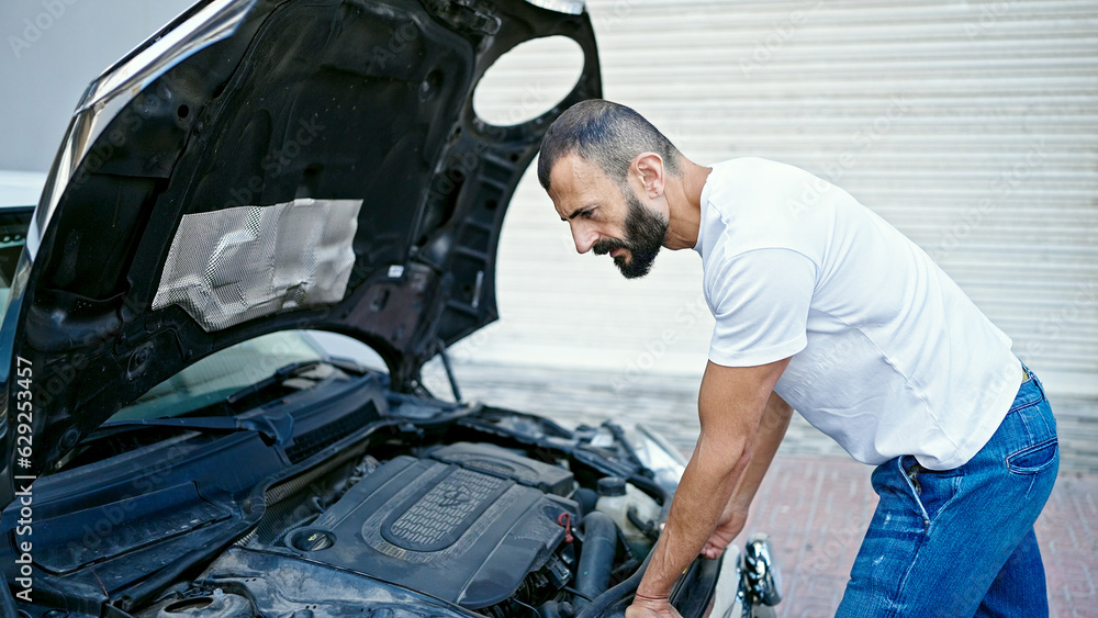 Young hispanic man looking motor car at street Young hispanic man looking motor car at street