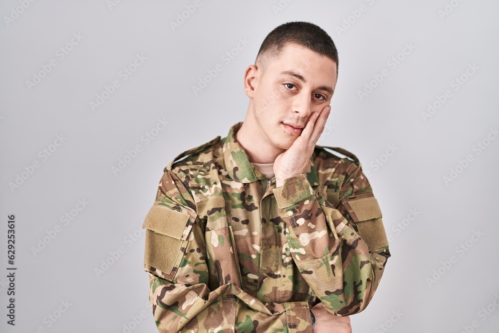 Young man wearing camouflage army uniform thinking looking tired and bored with depression problems with crossed arms.