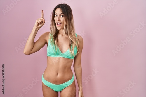 Young hispanic woman wearing bikini over pink background pointing finger up with successful idea. exited and happy. number one. © Krakenimages.com
