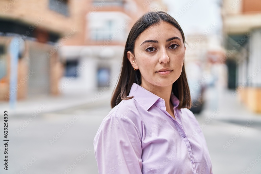 Young hispanic woman with relaxed expression standing at street