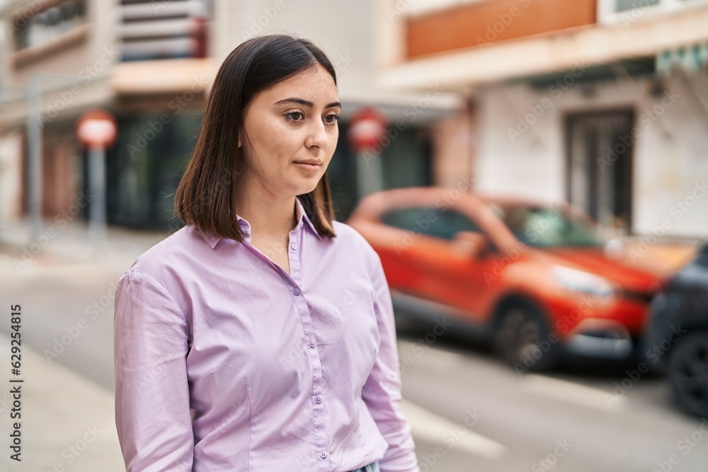 Young hispanic woman with relaxed expression standing at street