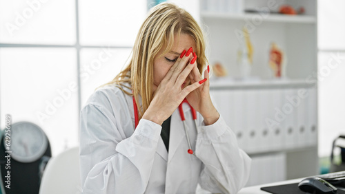 Young blonde woman doctor stressed working at clinic