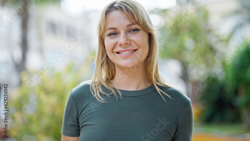 Young blonde woman smiling confident standing at park