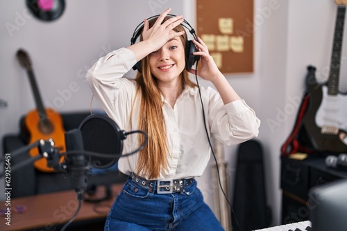 Young caucasian woman recording song at music studio stressed and frustrated with hand on head, surprised and angry face