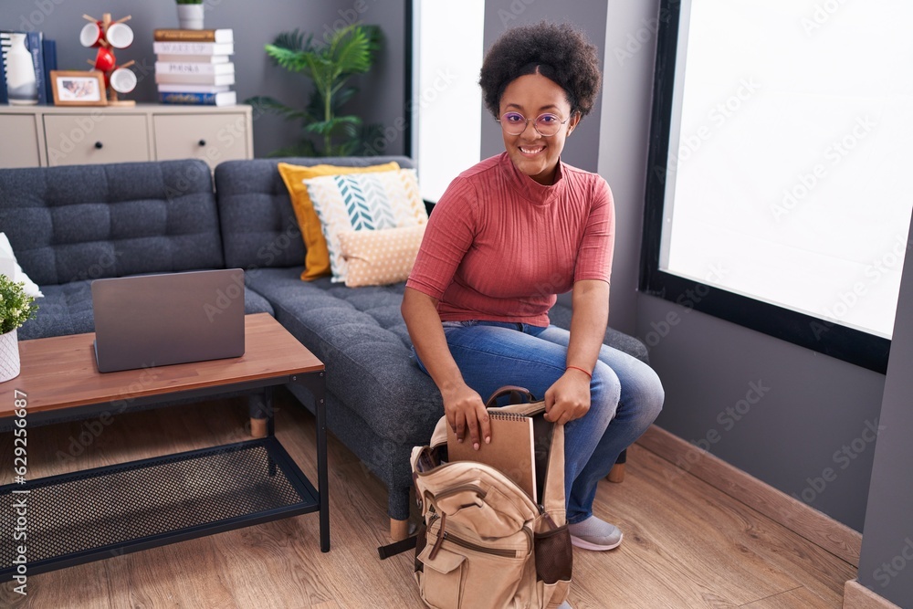 African american woman student holding notebook of backpack at home African american woman student holding notebook of backpack at home