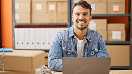 Young hispanic man ecommerce business worker using laptop smiling at office