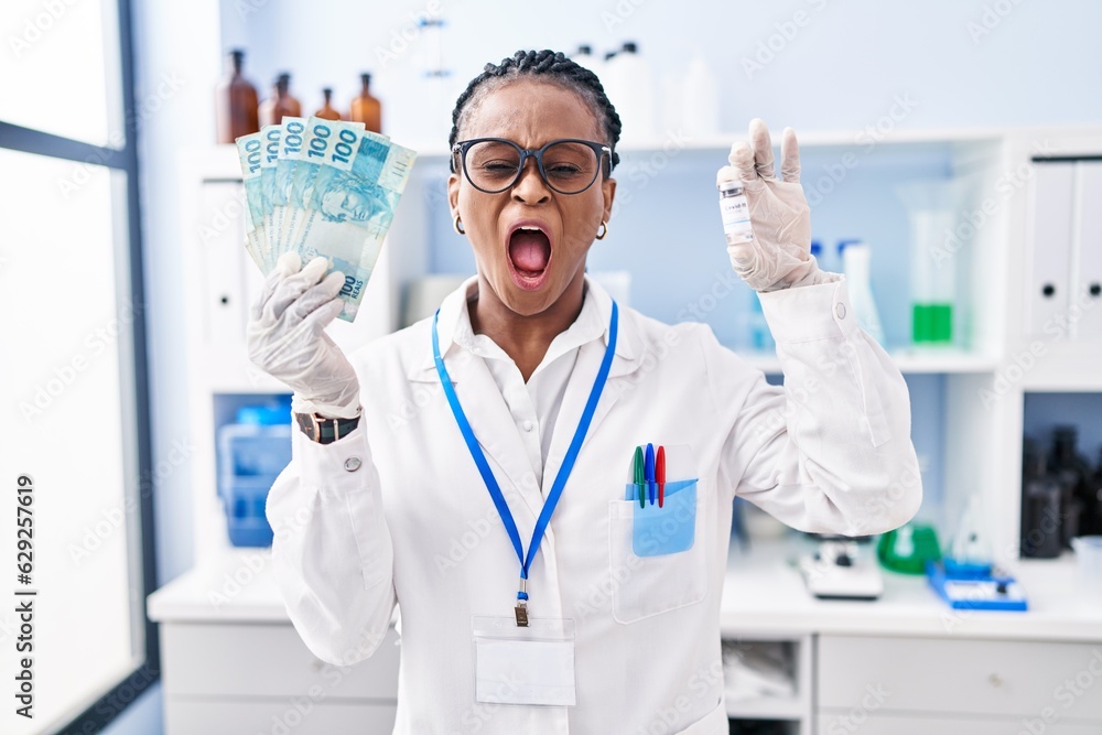 African woman with braids working at scientist laboratory holding money angry and mad screaming frustrated and furious, shouting with anger. rage and aggressive concept. African woman with braids working at scientist laboratory holding money angry and mad screaming frustrated and furious, shouting with anger. rage and aggressive concept.