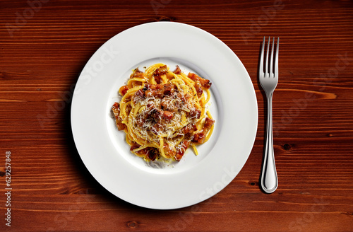 Top view of plate with spaghetti carbonara on wooden table