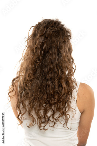 Rear view of a woman with long brown wavy hair on a white background