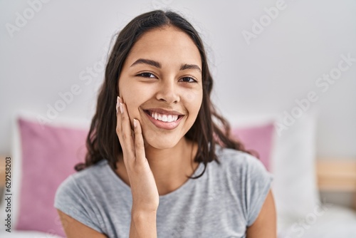 Young african american woman smiling confident touching face at bedroom