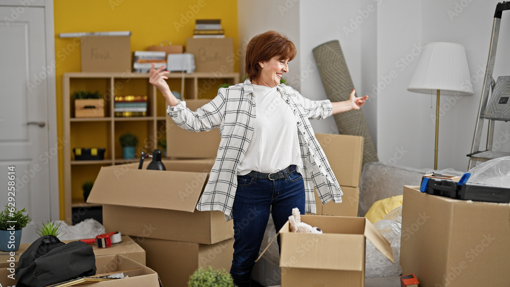 Middle age woman smiling confident standing with arms opened at new home Middle age woman smiling confident standing with arms opened at new home