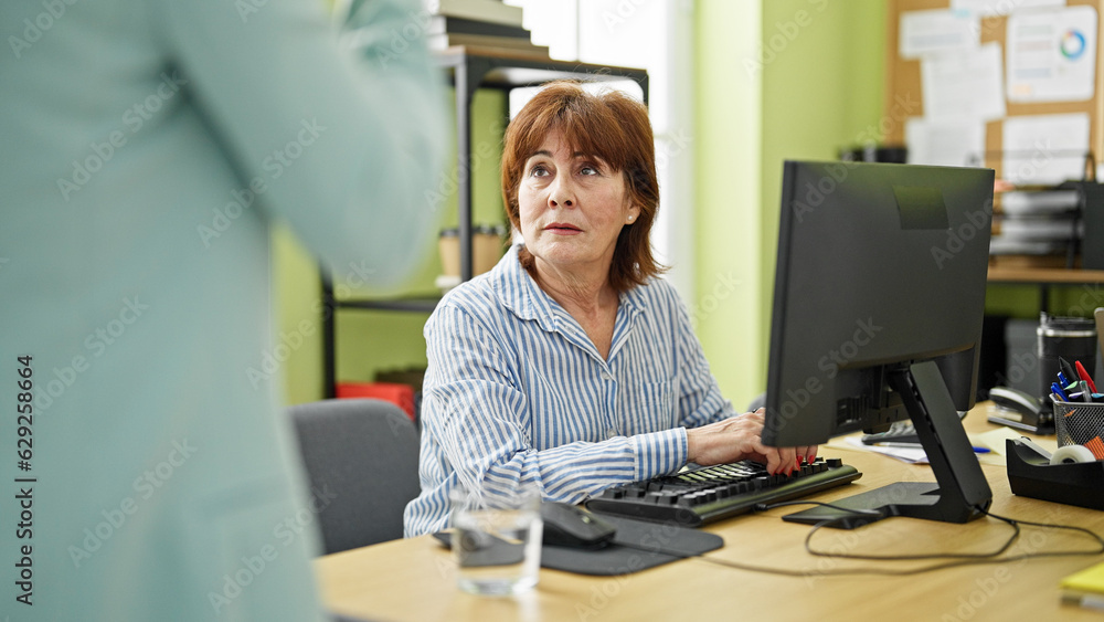 Middle age woman business worker speaking with boss at office Middle age woman business worker speaking with boss at office