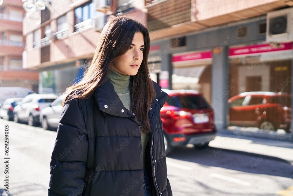 Young beautiful hispanic woman looking to the side with serious expression at street