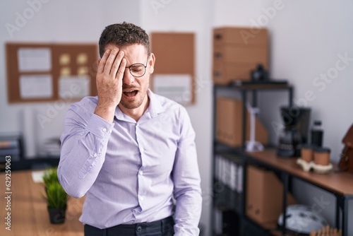 Young hispanic man at the office yawning tired covering half face, eye and mouth with hand. face hurts in pain.