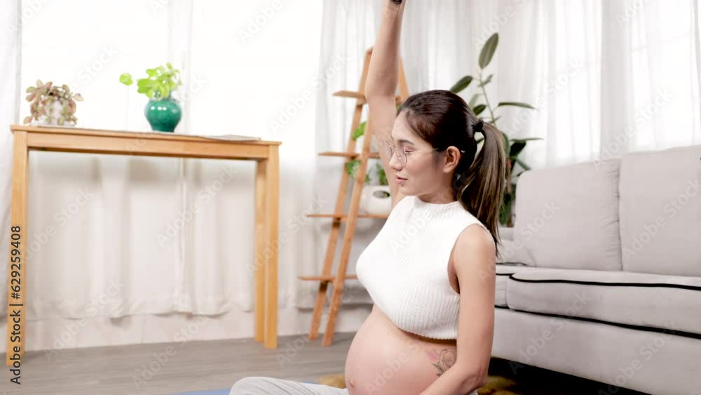 Beautiful pregnant Asian mother sitting with eyes closed doing yoga in living room for preparing childbirth. health care motherhood meditation for maternity, pregnancy woman lifestyle. Beautiful pregnant Asian mother sitting with eyes closed doing yoga in living room for preparing childbirth. health care motherhood meditation for maternity, pregnancy woman lifestyle.