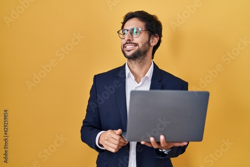Handsome latin man working using computer laptop looking away to side with smile on face, natural expression. laughing confident.