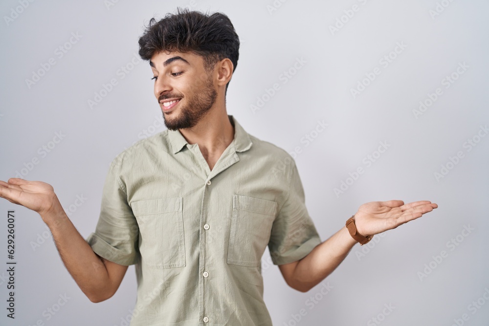 Arab man with beard standing over white background smiling showing both hands open palms, presenting and advertising comparison and balance Arab man with beard standing over white background smiling showing both hands open palms, presenting and advertising comparison and balance