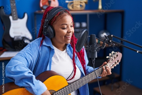 African american woman musician singing song playing classical guitar at music studio