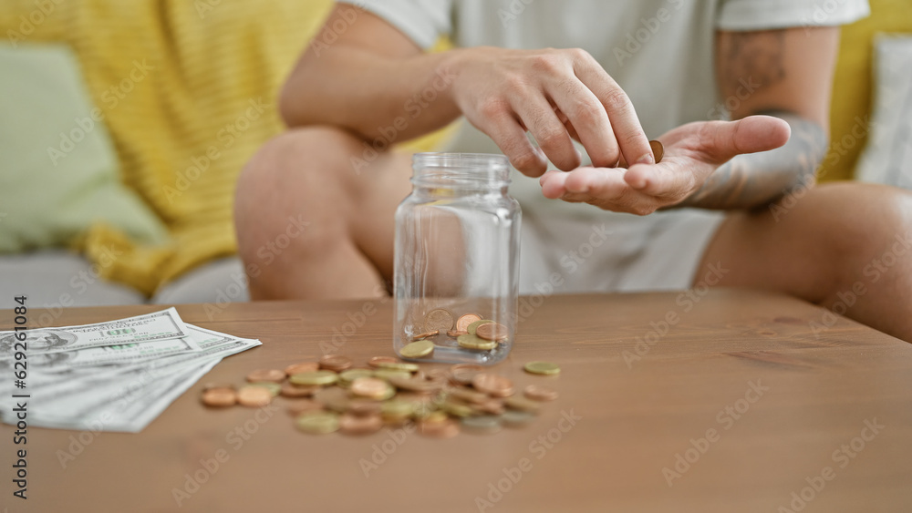 Young hispanic man inserting coins on bottle at park Young hispanic man inserting coins on bottle at park
