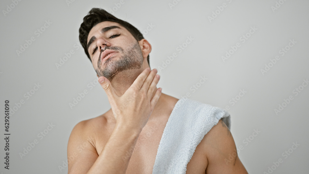 Obraz premium Young hispanic man standing shirtless applying beard treatment over isolated white background